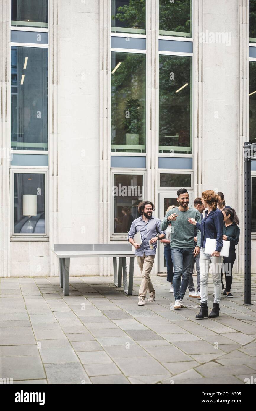 Multi-ethnic coworkers walking against office building Stock Photo