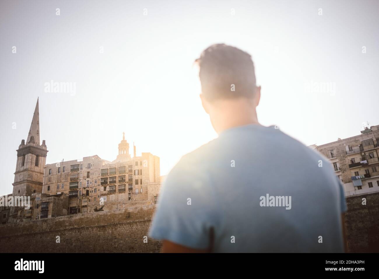 Rear view of man looking at building in city against sky Stock Photo