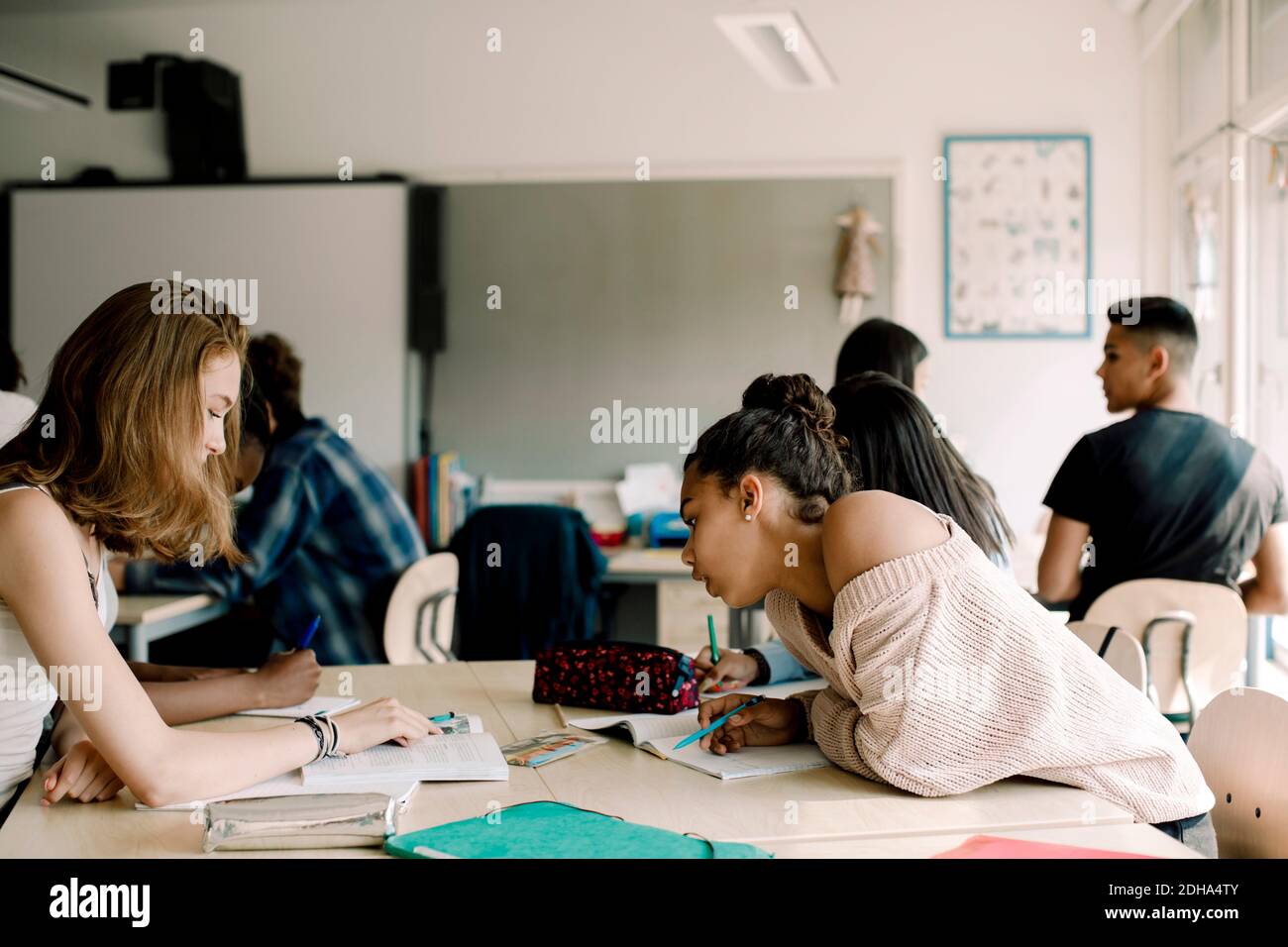 Teenage students discussing over book in classroom Stock Photo