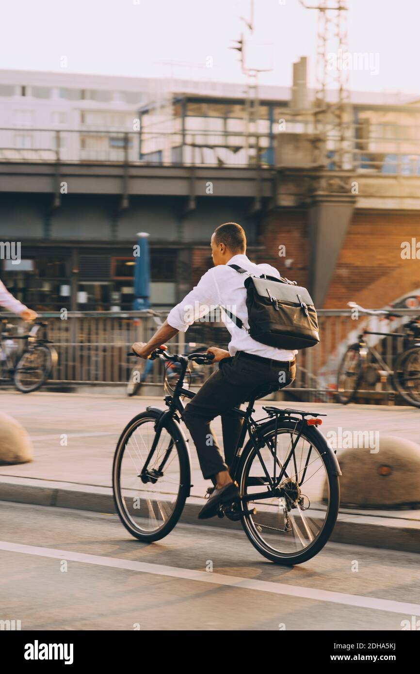 Rare view of male executive riding bicycle on street in city against sky Stock Photo