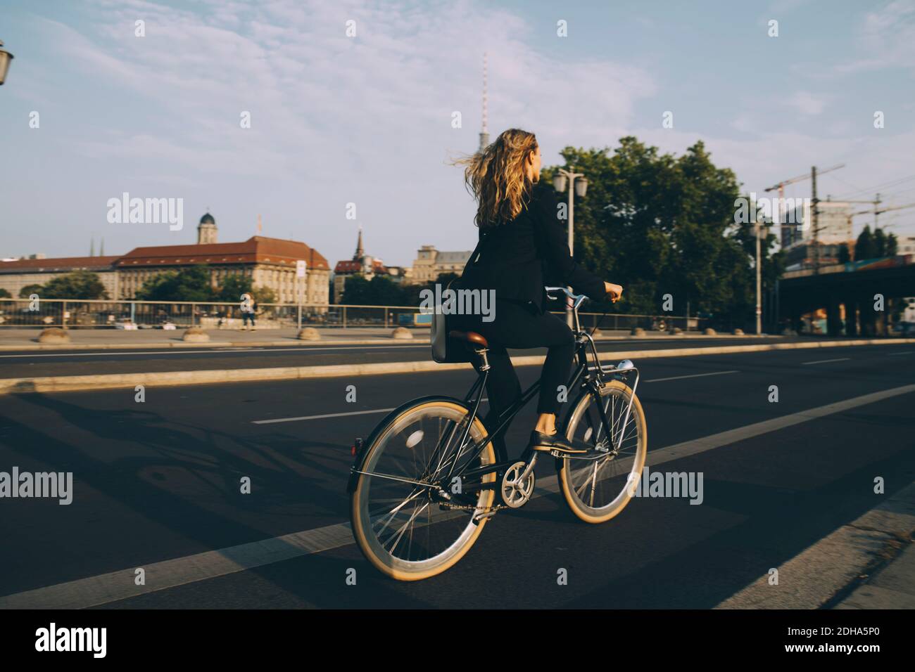 Rare view of female executive riding bicycle on road in city against sky Stock Photo