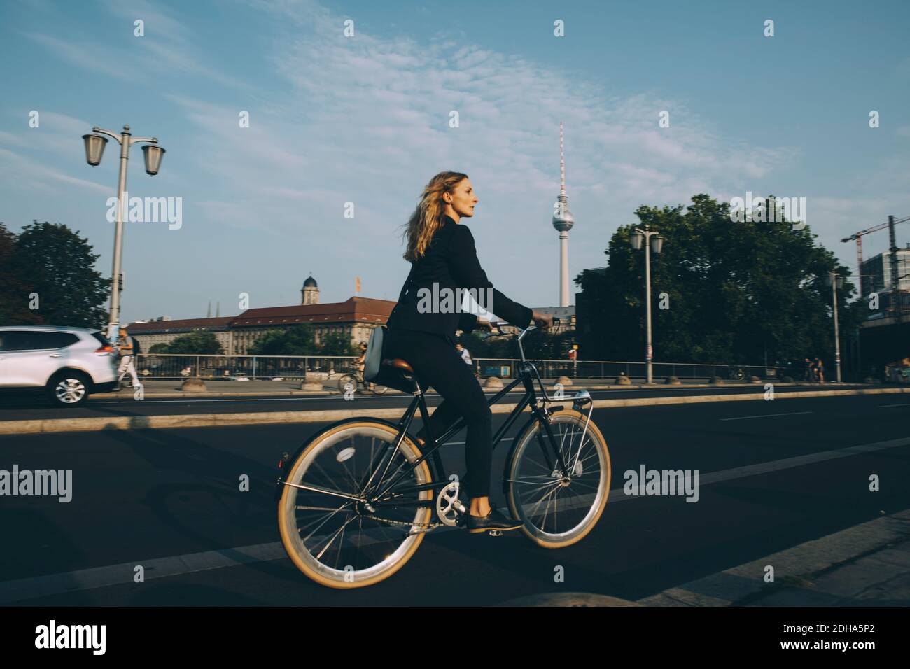 Side view of businesswoman riding bicycle on street in city Stock Photo