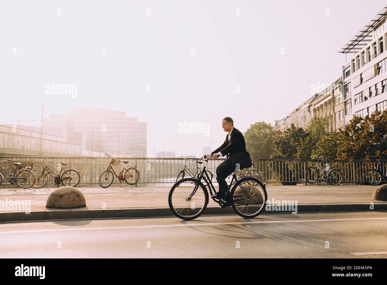 Full length of mature man riding bicycle on road in city against sky Stock Photo