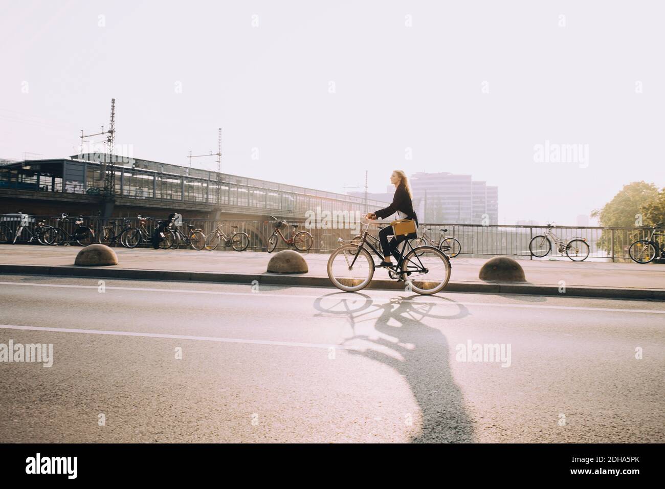 Female entrepreneur riding bicycle on street in city against sky Stock Photo