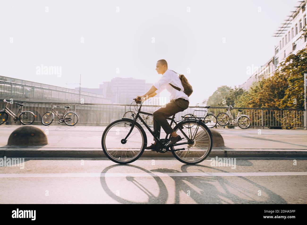 Full length of businessman riding bicycle on street in city against sky Stock Photo