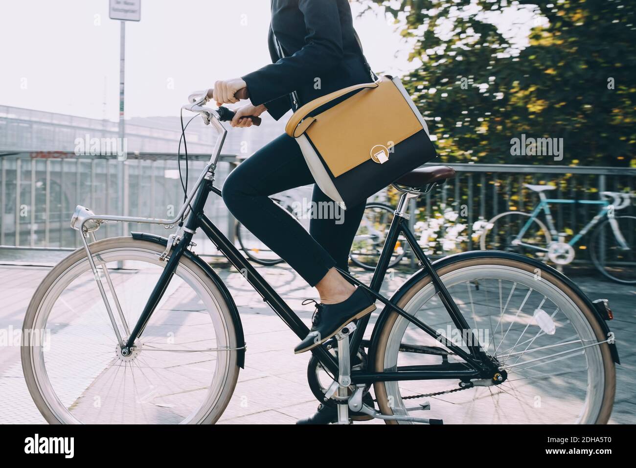 Low section of businesswoman riding bicycle on road in city Stock Photo
