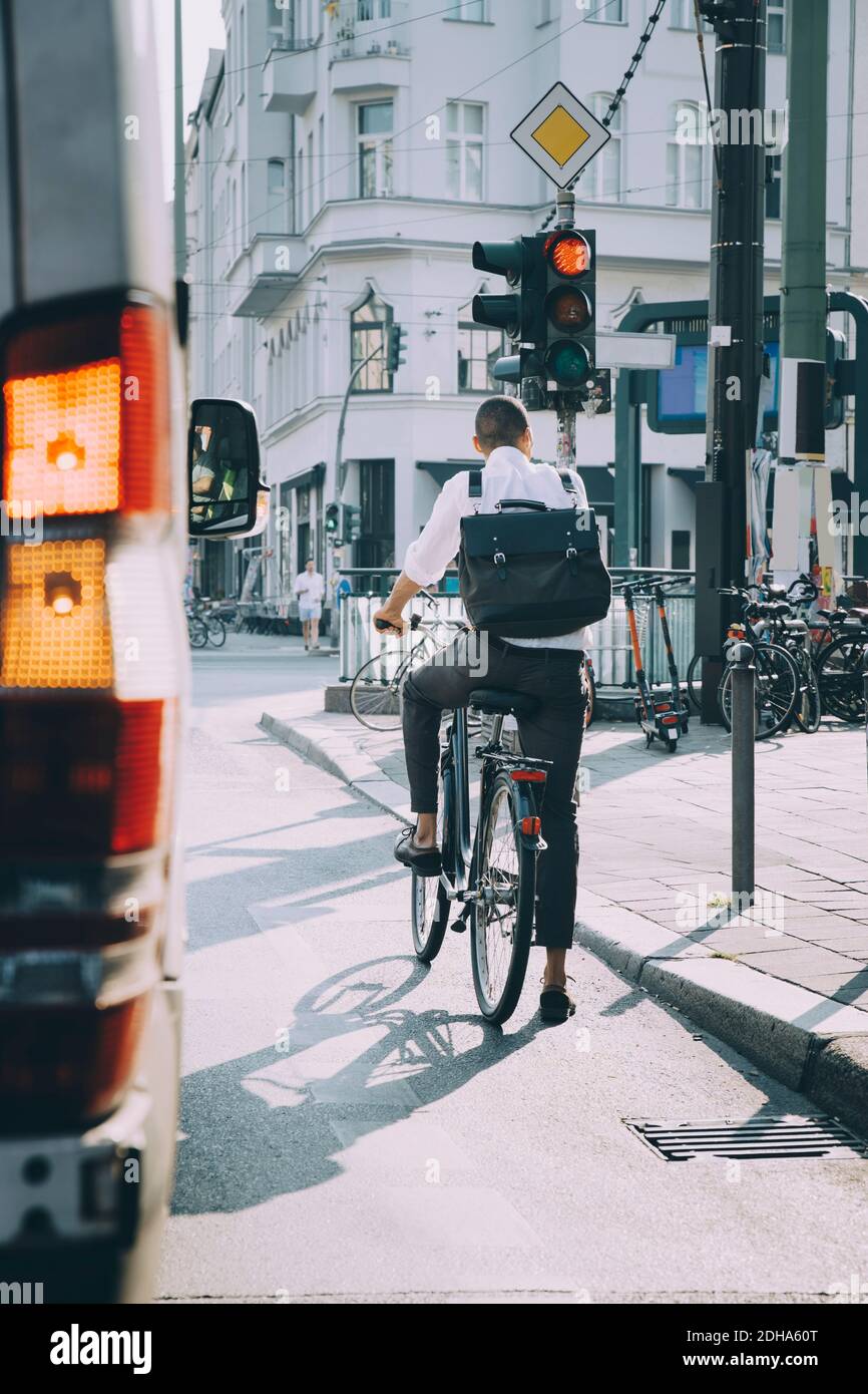 Rear view of male entrepreneur riding bicycle on road in city Stock Photo