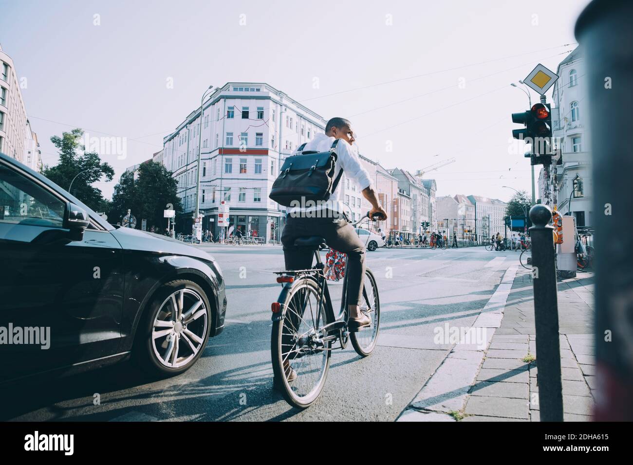 Full length of male entrepreneur riding bicycle on road in city against sky Stock Photo