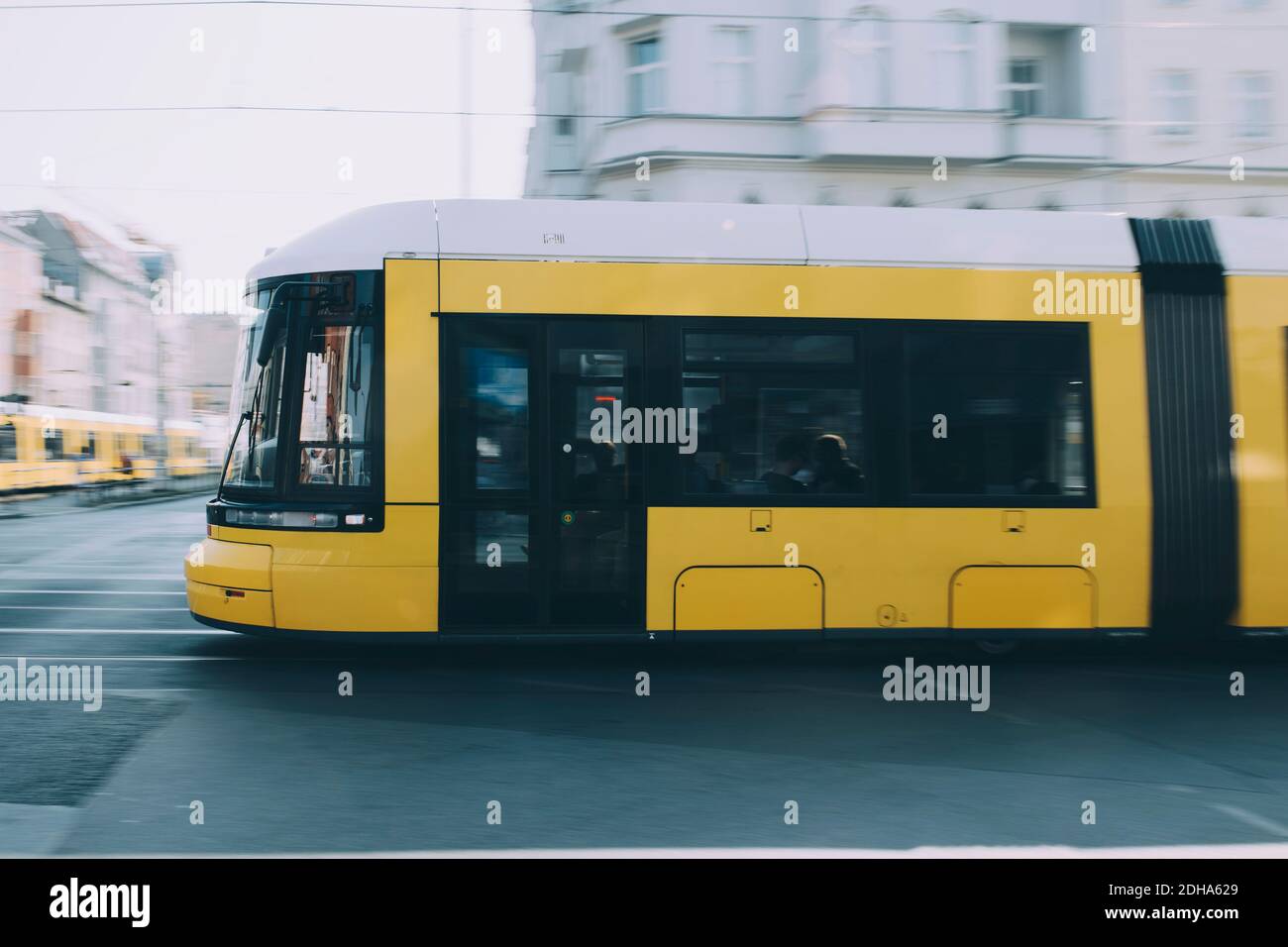 Yellow bus by building on road in city Stock Photo