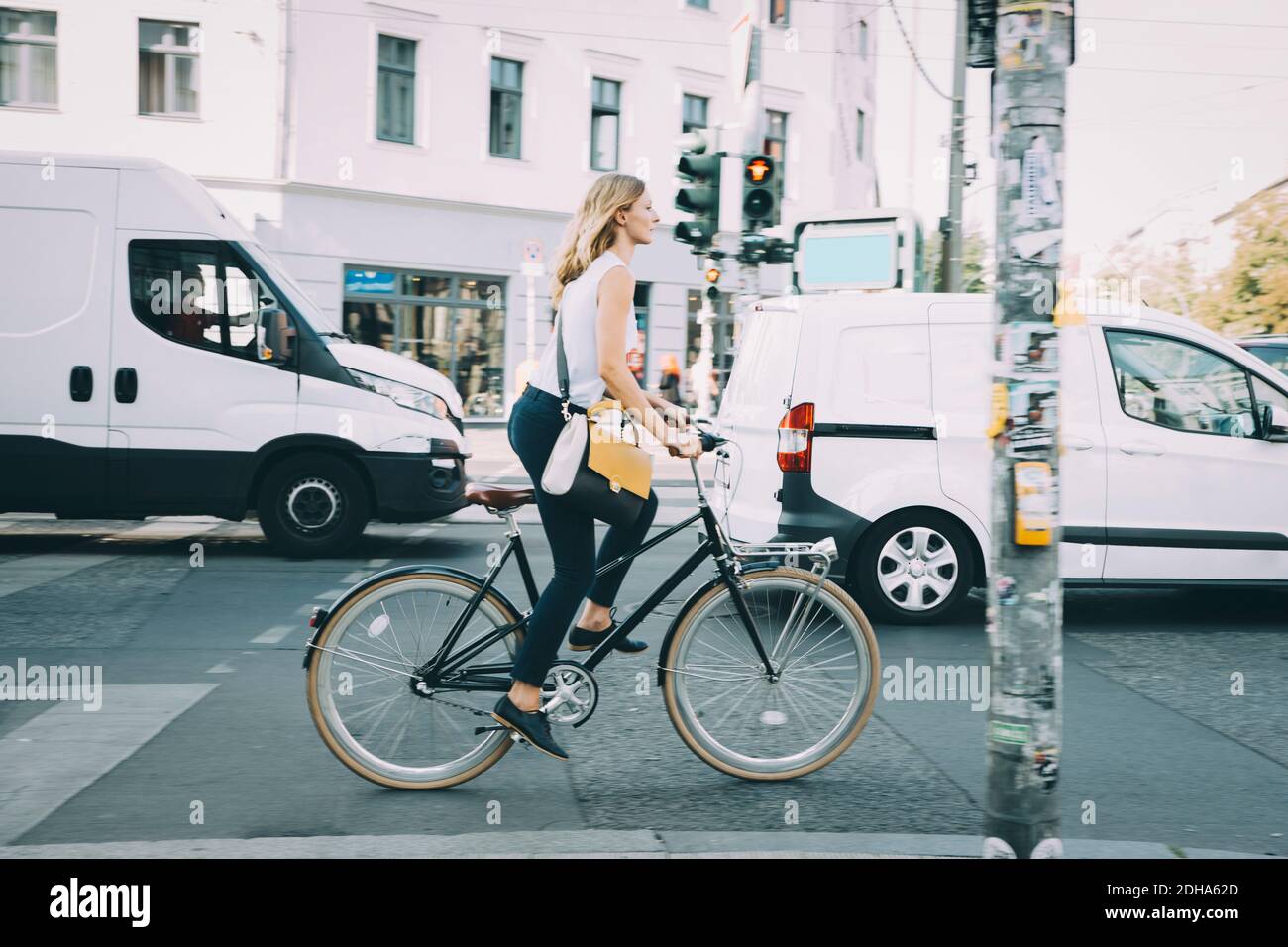 Full length of young businesswoman riding bicycle on road in city Stock Photo