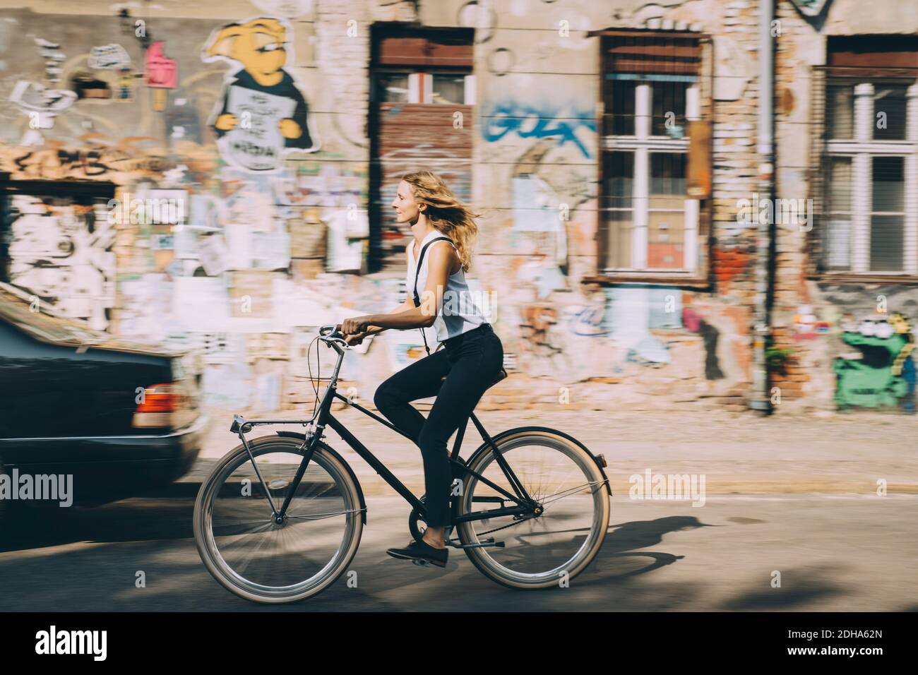 Side view of young businesswoman riding bicycle against building in city Stock Photo