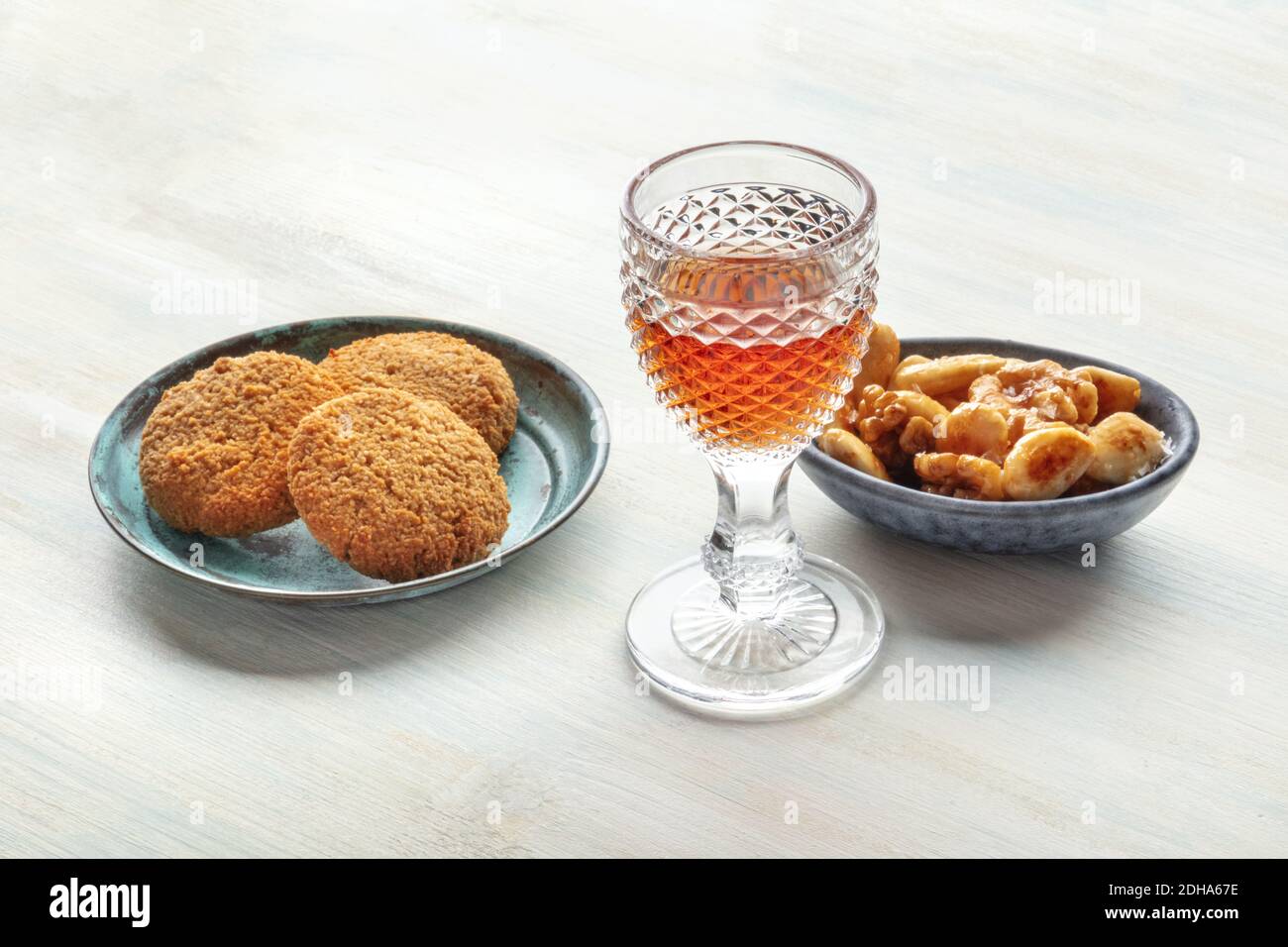 A photo of a glass of fortified wine with cookies and nuts Stock Photo