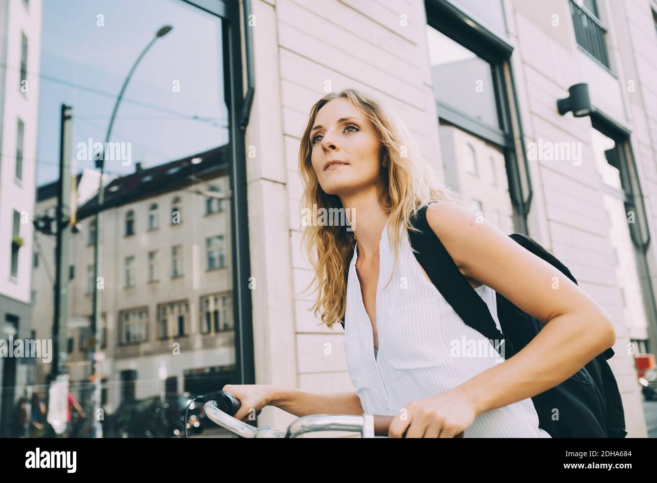 Female entrepreneur with bicycle standing against building in city Stock Photo
