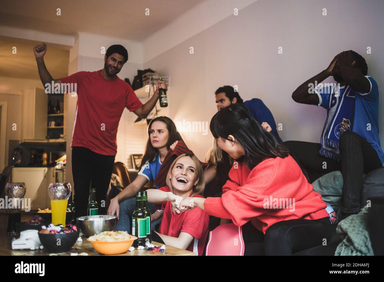 Cheerful red team celebrating while blue team sitting in disappointment at home Stock Photo