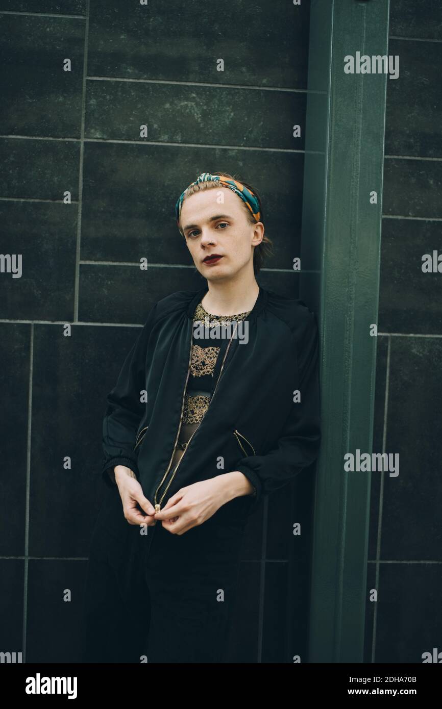 Young man standing by wall hi-res stock photography and images - Alamy