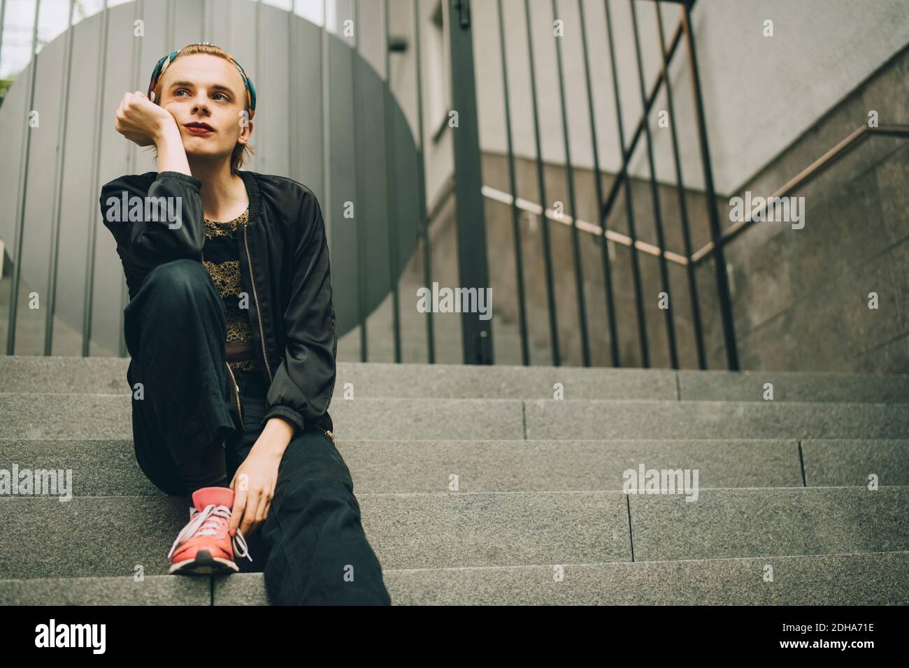 Contemplating young man looking away while sitting on steps Stock Photo
