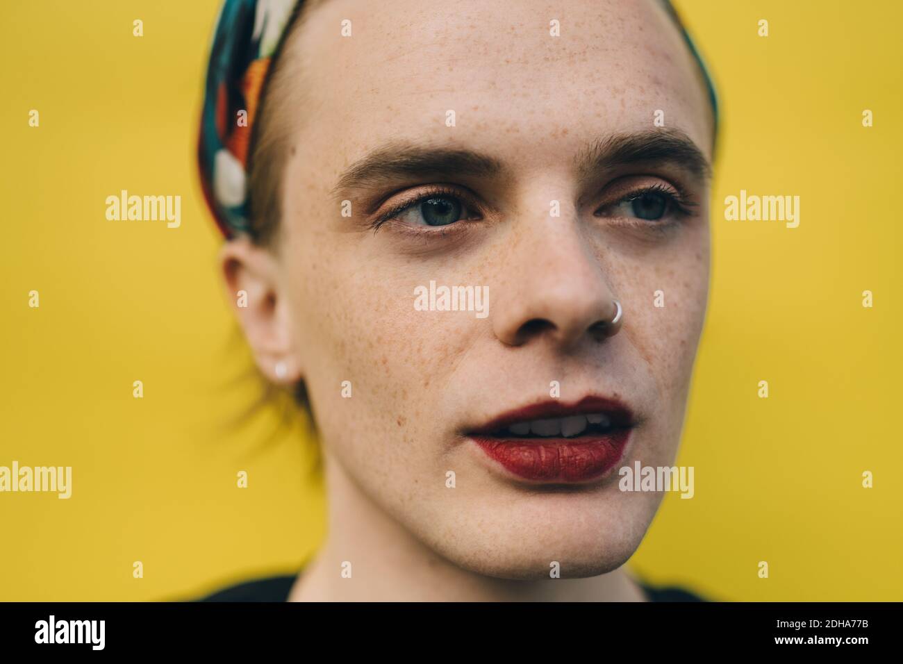 Confident young man looking away while standing against yellow background Stock Photo