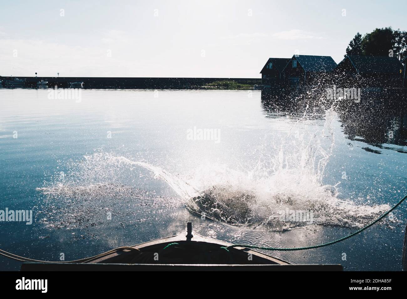 Splashing water in lake by boat against sky on sunny day Stock Photo