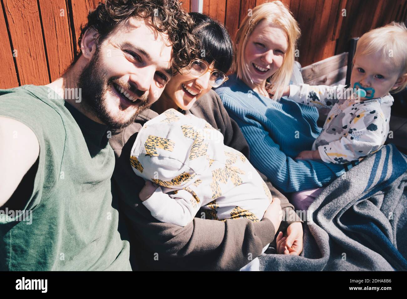 Portrait of cheerful man and women with children sitting at holiday villa on sunny day Stock Photo