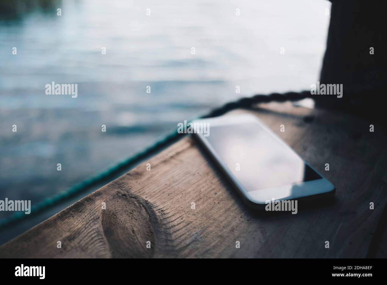 Close-up of smart phone on jetty over lake Stock Photo