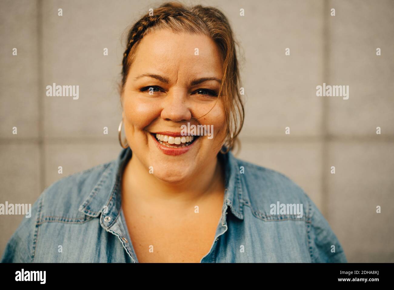 Portrait of smiling woman against wall Stock Photo - Alamy