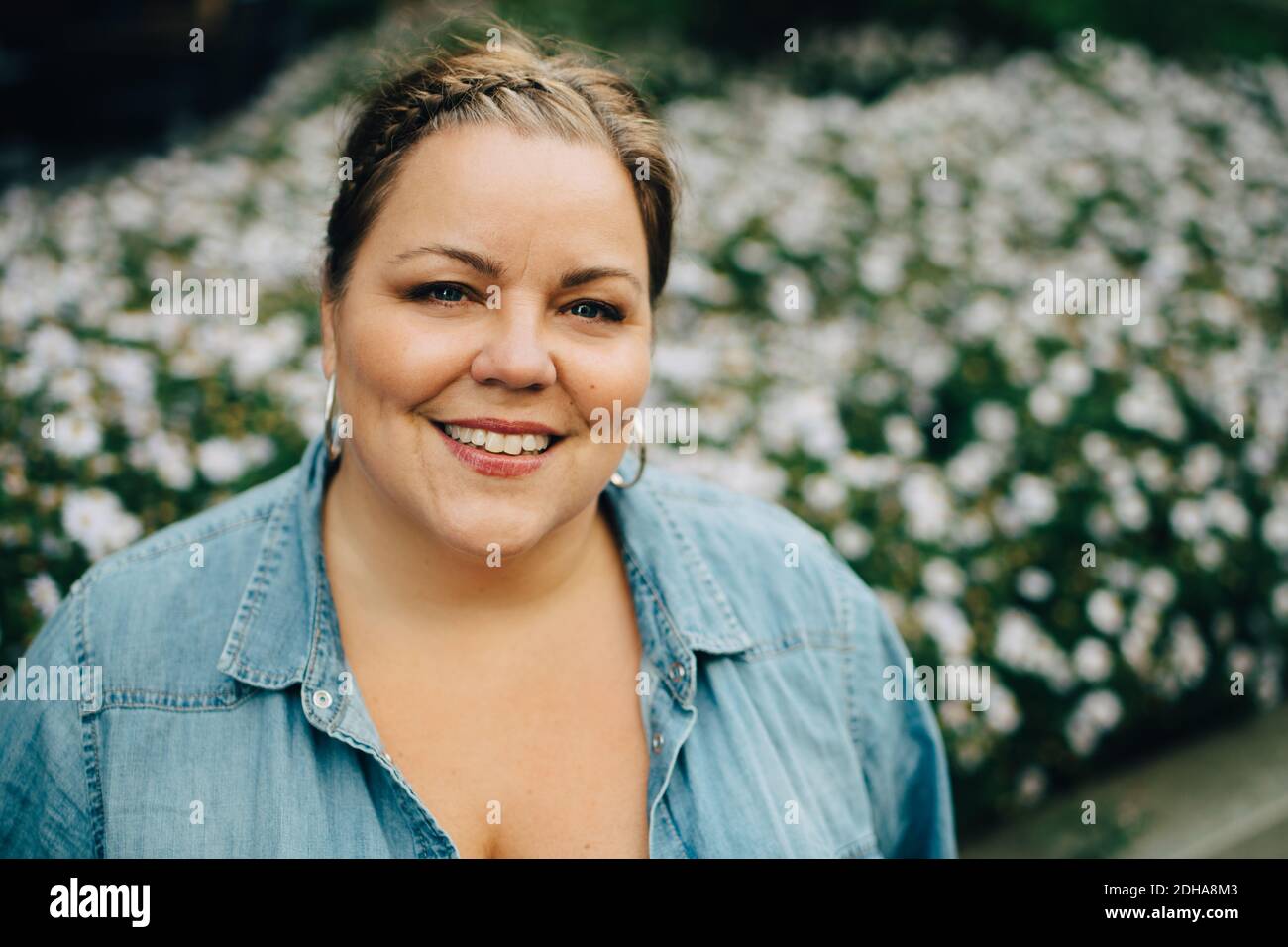 Portrait of smiling woman against flowering plants Stock Photo