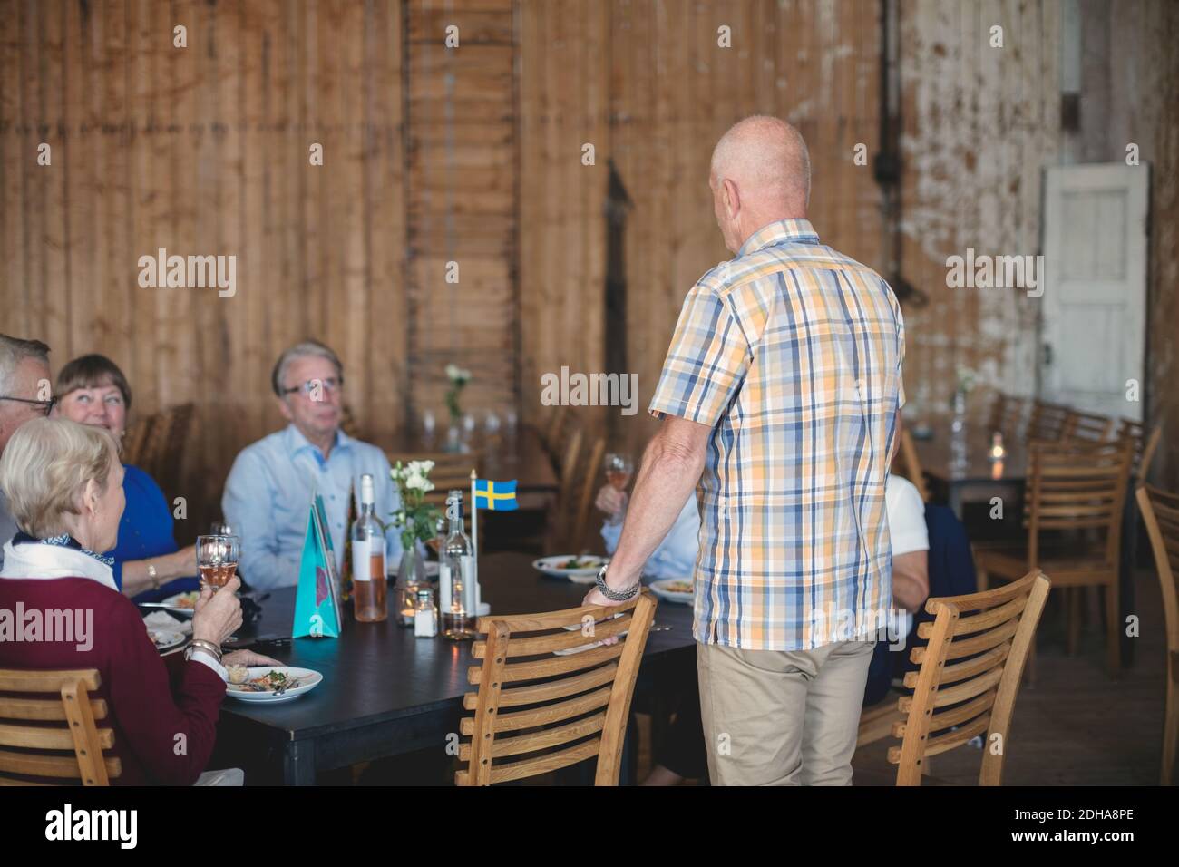 Senior man giving speech to friends while having lunch in restaurant Stock Photo