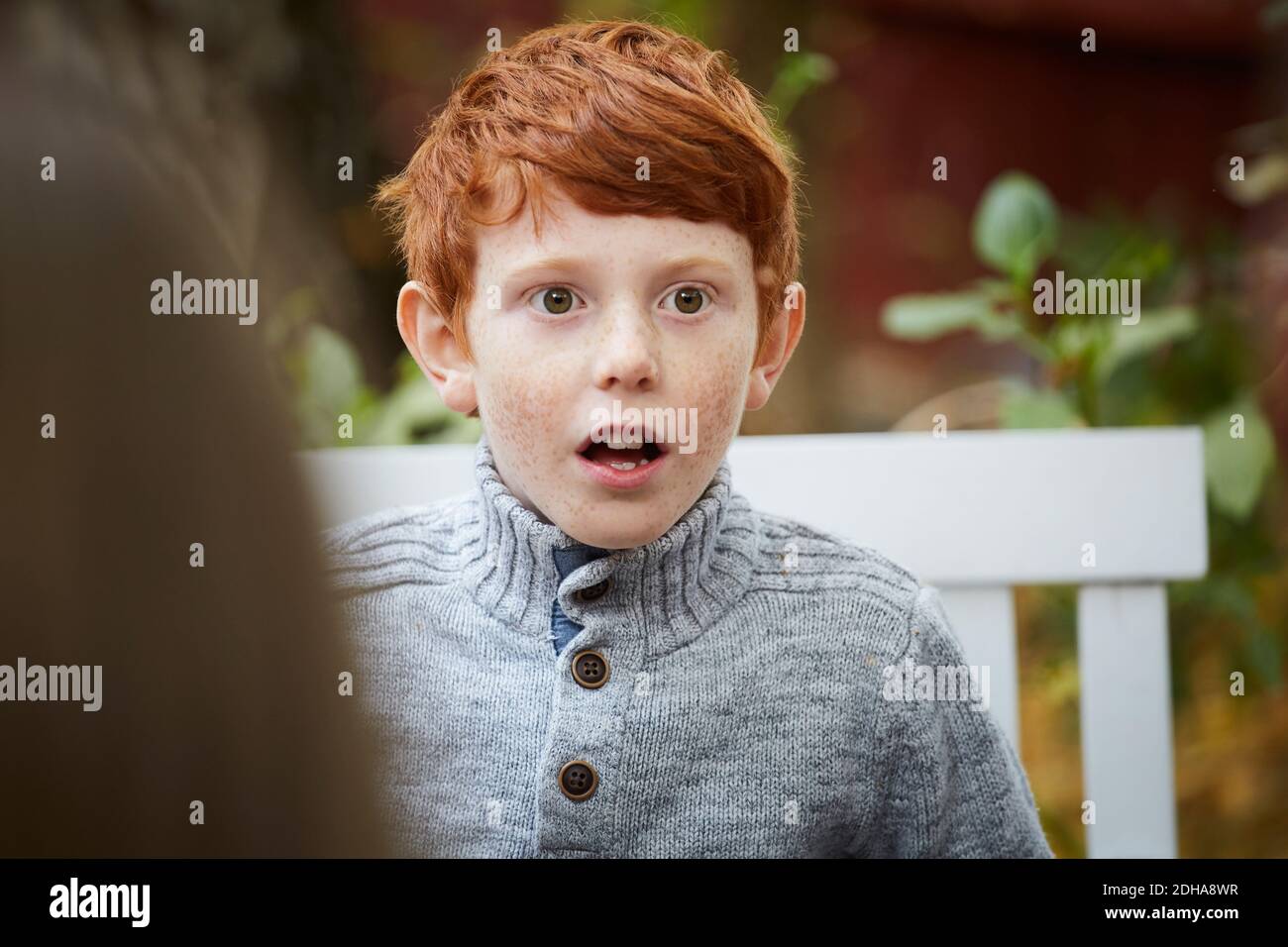 Surprised boy looking away while sitting in yard Stock Photo