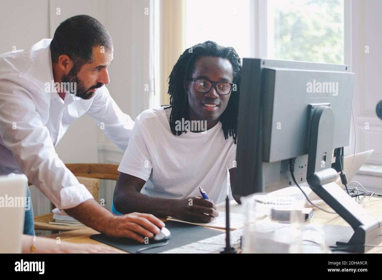 Businessmen discussing while using computer at desk in creative office Stock Photo