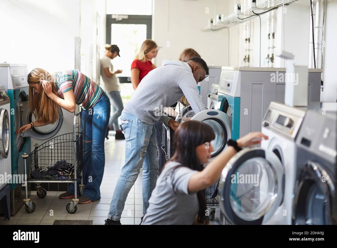 University students using washing machines at campus laundromat Stock Photo