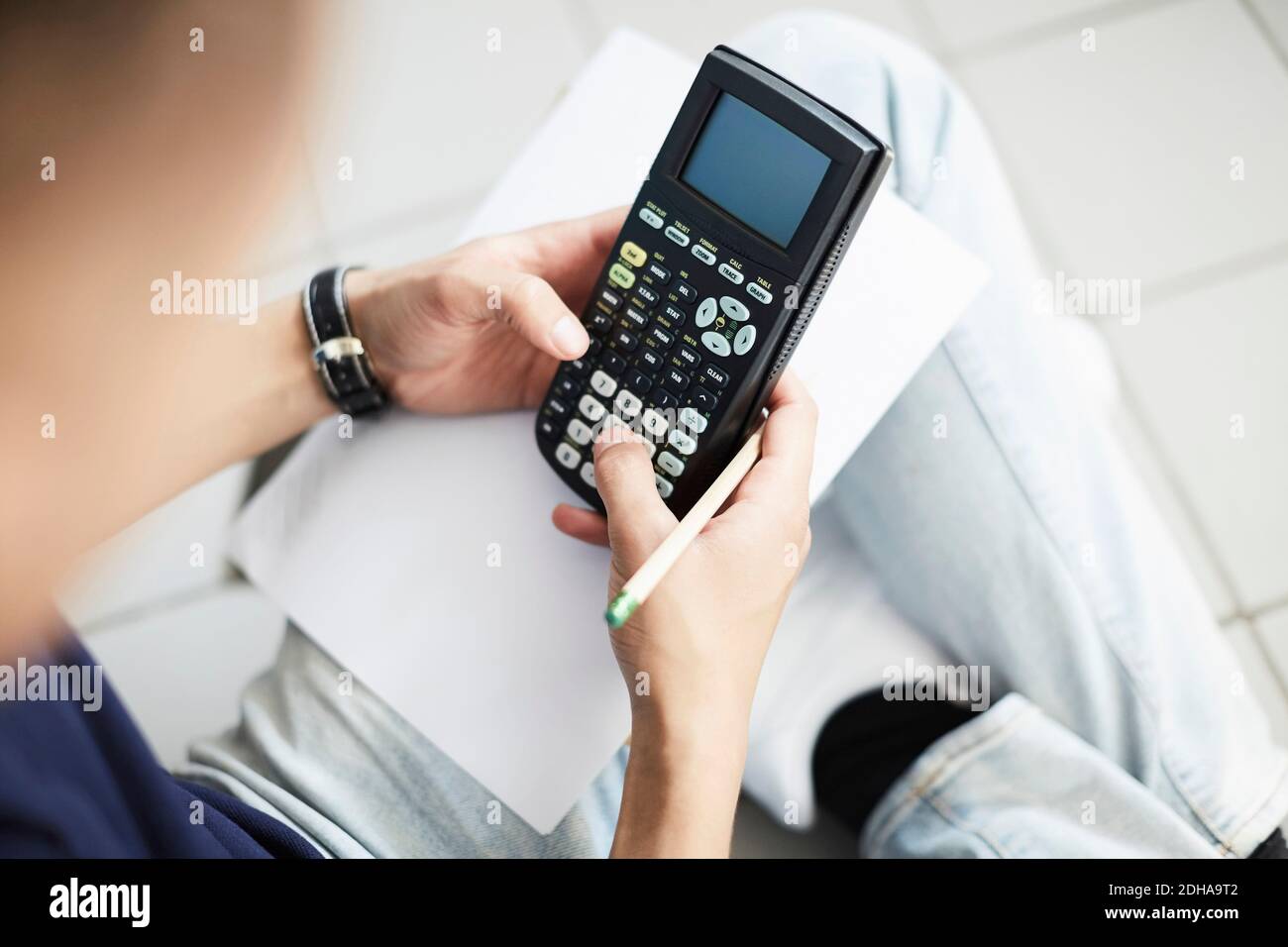 Cropped image of man using calculator while studying at laundromat Stock Photo