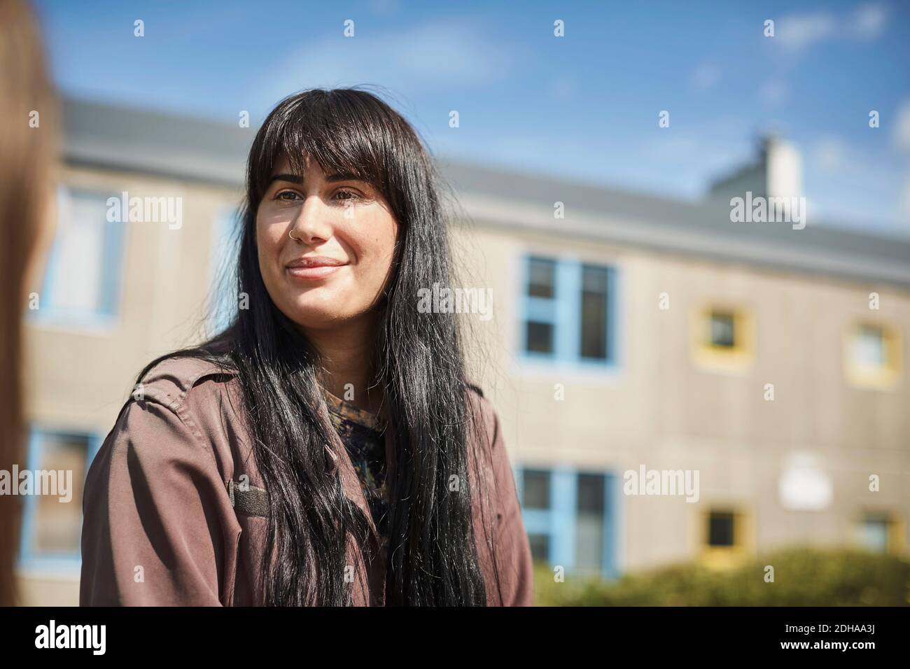Smiling young woman with long black hair at university campus Stock Photo