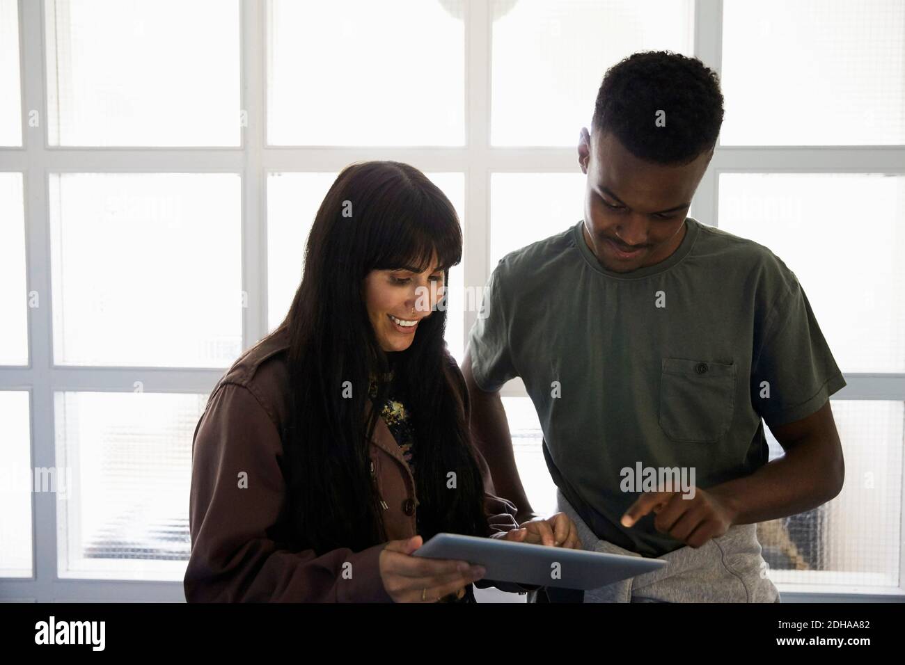 Smiling friends using digital tablet while standing at university Stock Photo