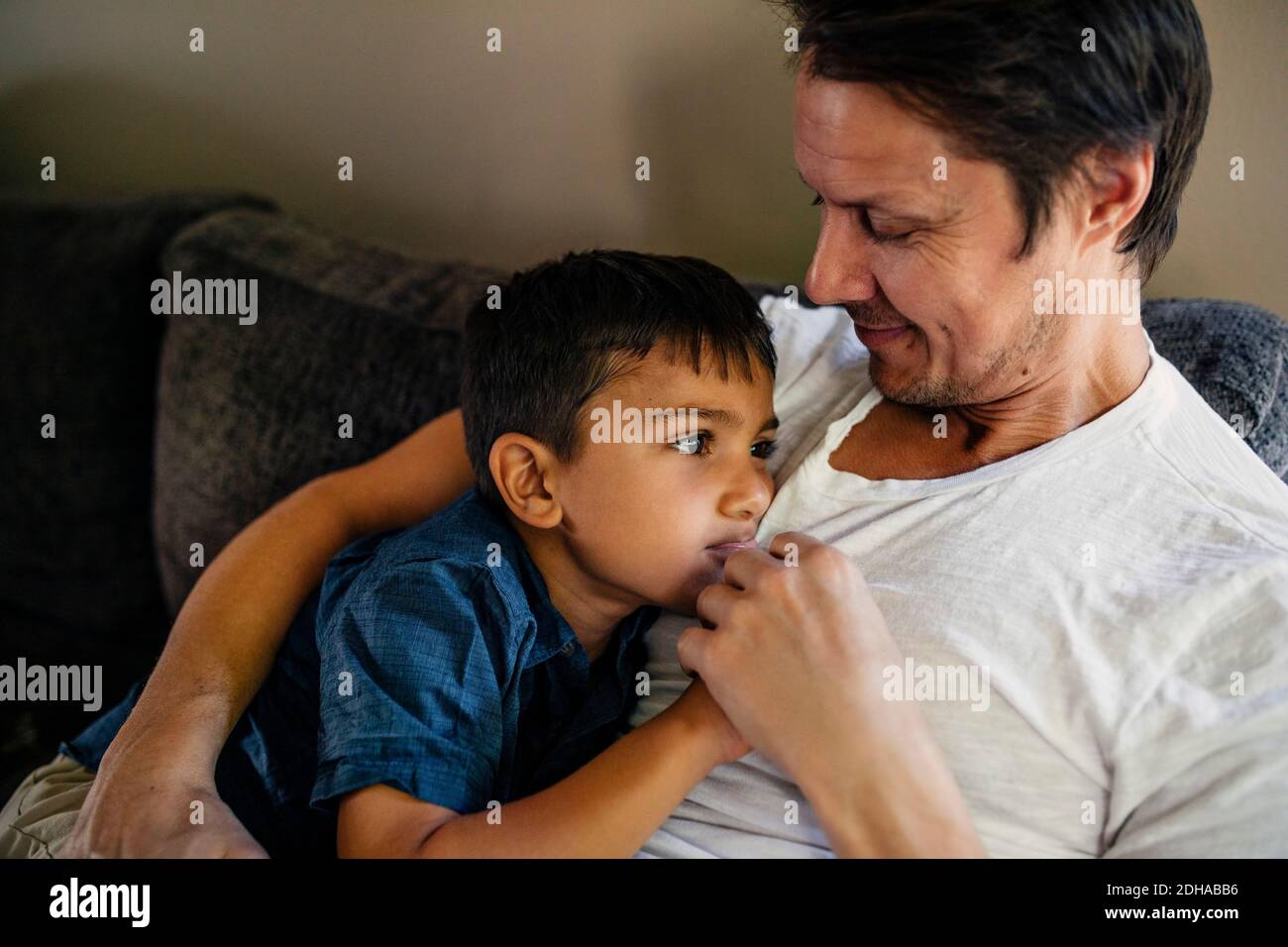Smiling father with son sitting on sofa at home Stock Photo