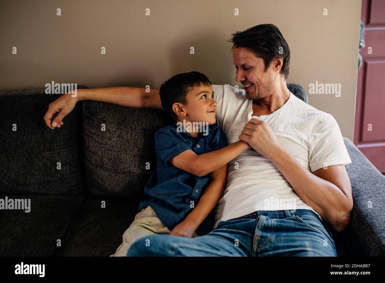 Happy father with son sitting on sofa at home Stock Photo