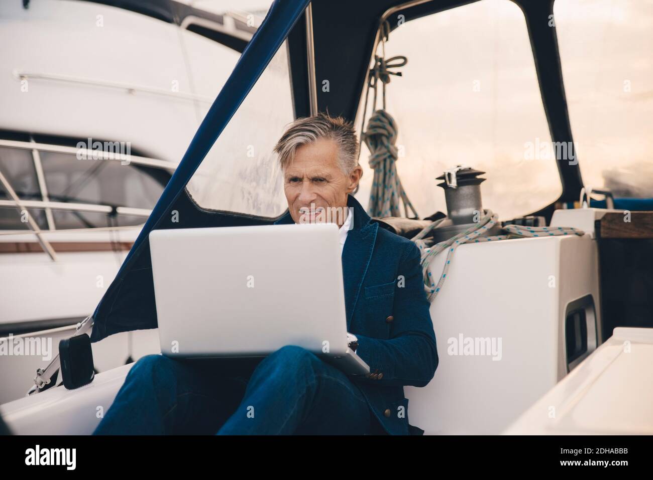 Senior man using laptop while sitting in yacht Stock Photo