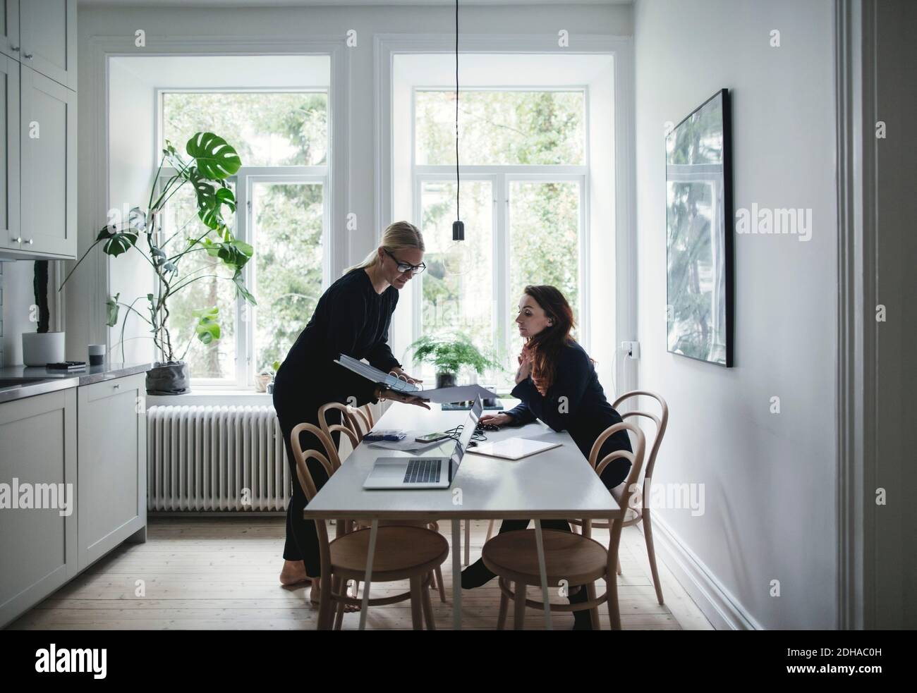 Female colleagues discussing over document at table in home office Stock Photo