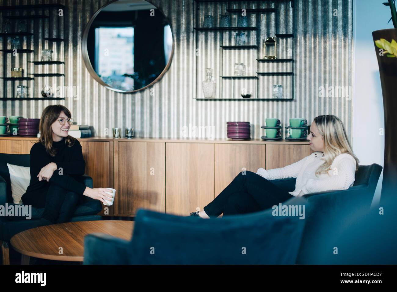 Two smiling colleagues sitting at coffee table in office Stock Photo
