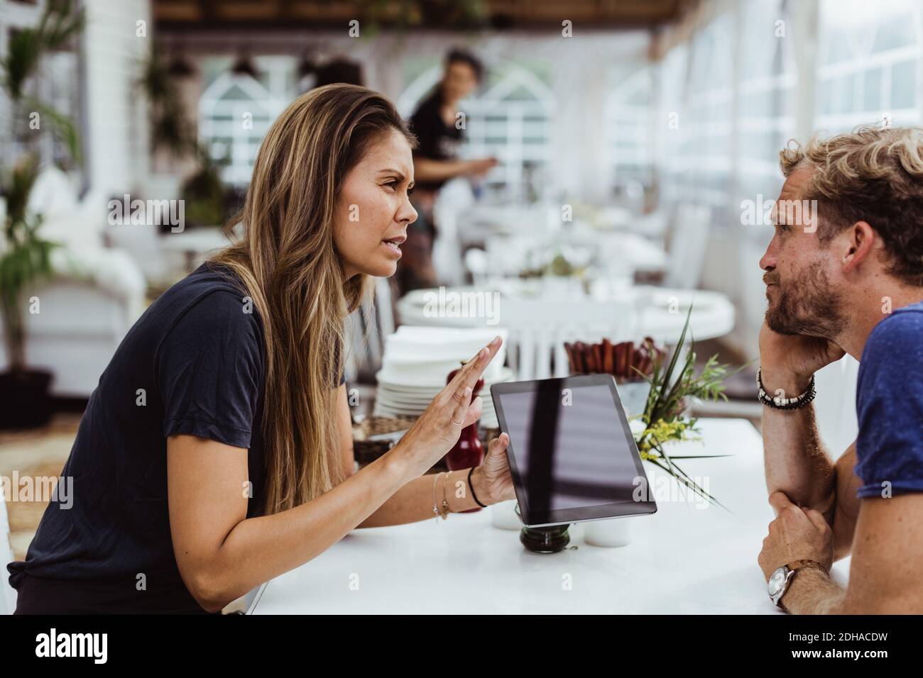 Female owner taking order from customer while using digital tablet in restaurant Stock Photo