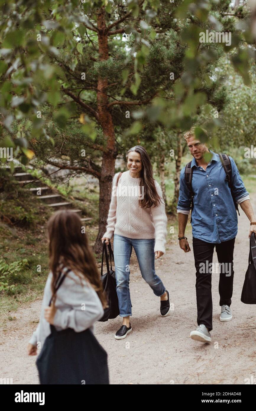 Full length of parents looking at daughter while walking on footpath in forest Stock Photo