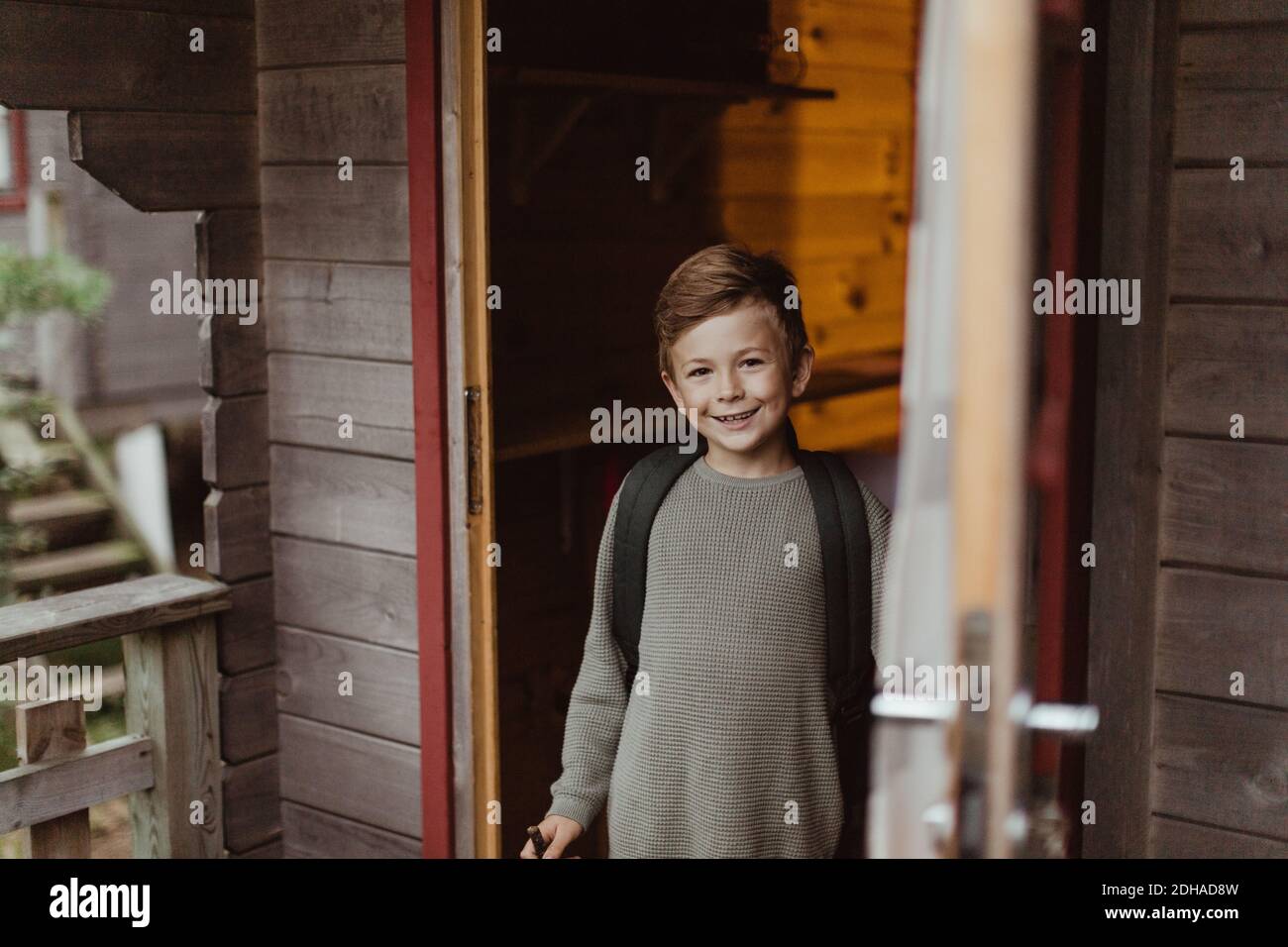 Portrait of smiling boy standing at doorway of house during vacation Stock Photo