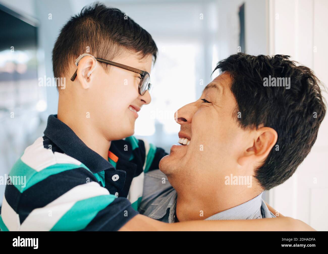Close-up of happy father carrying smiling disabled son while standing at home Stock Photo