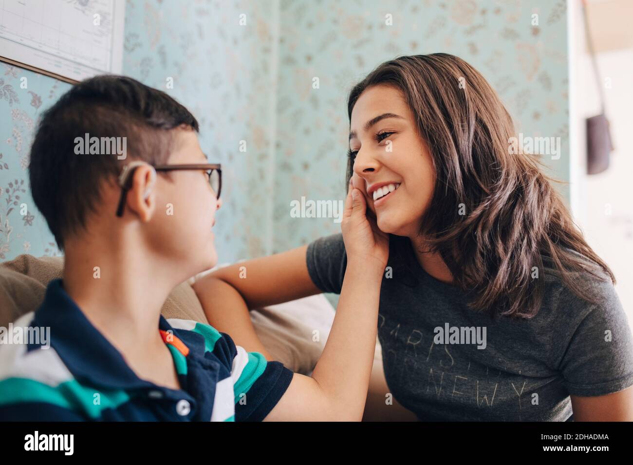 Disabled boy touching sister while sitting on sofa at home Stock Photo