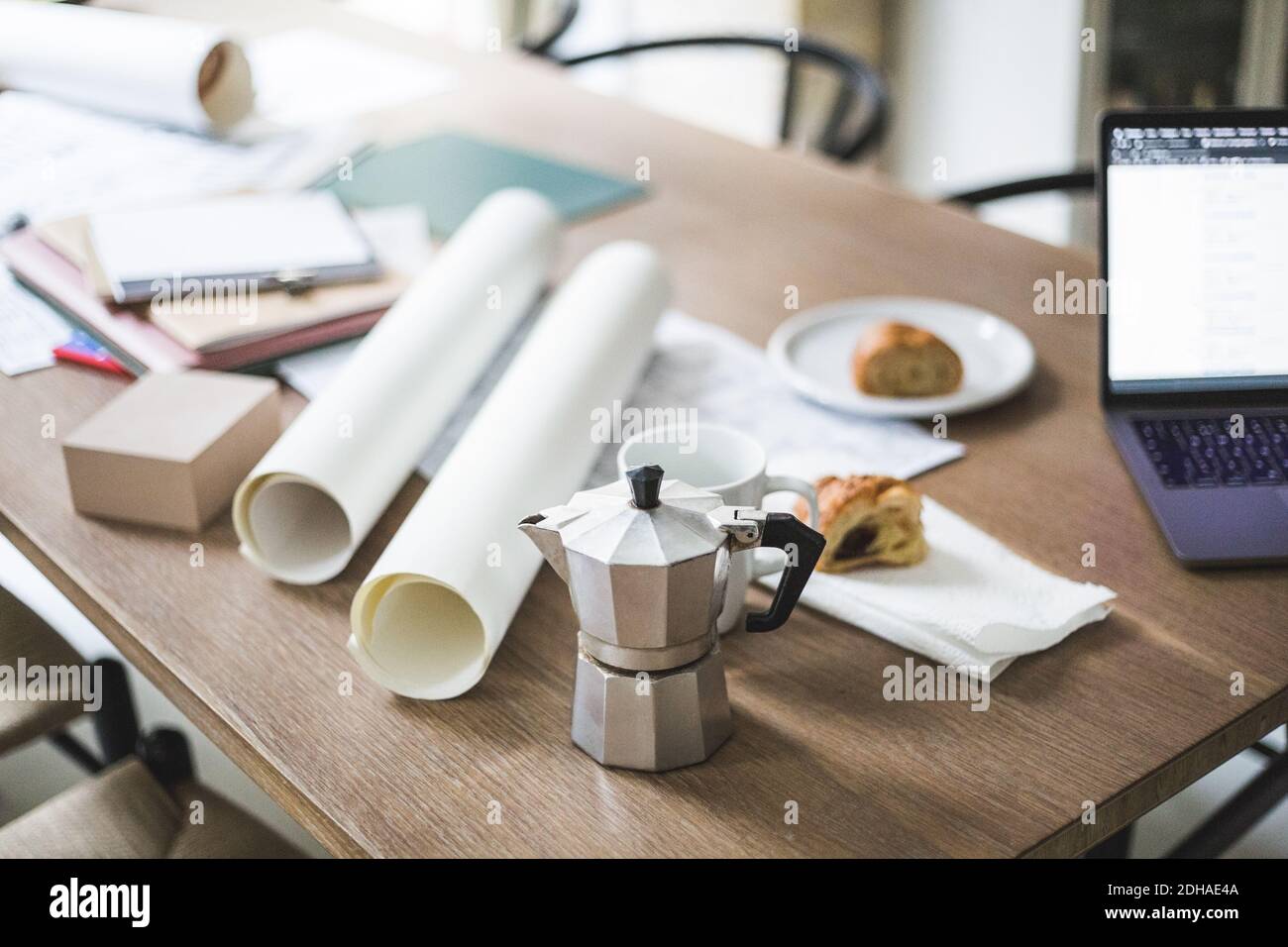 High angle view of teapot with documents rolled up on table Stock Photo