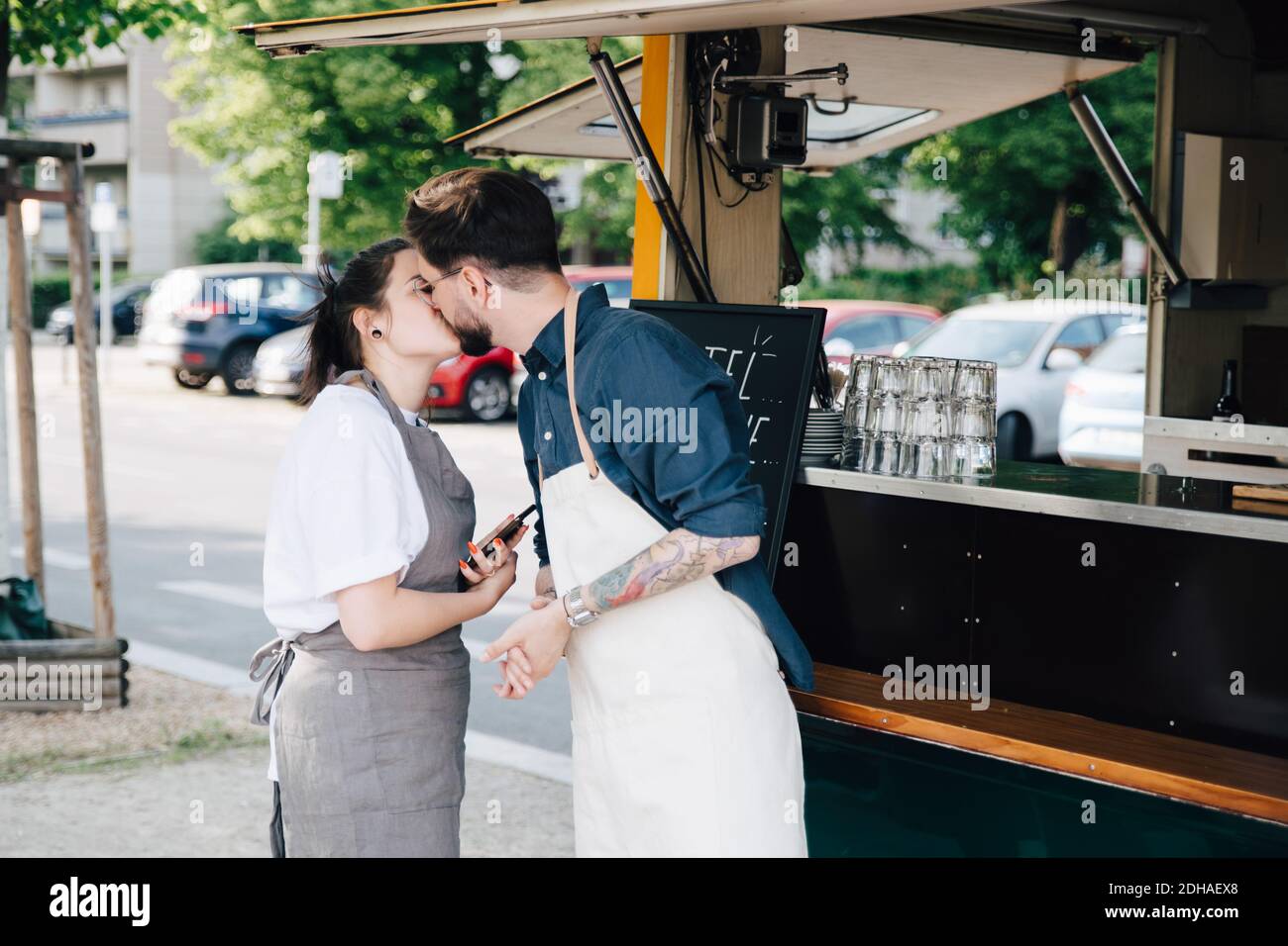 Male and female entrepreneurs kissing while standing by food truck Stock Photo