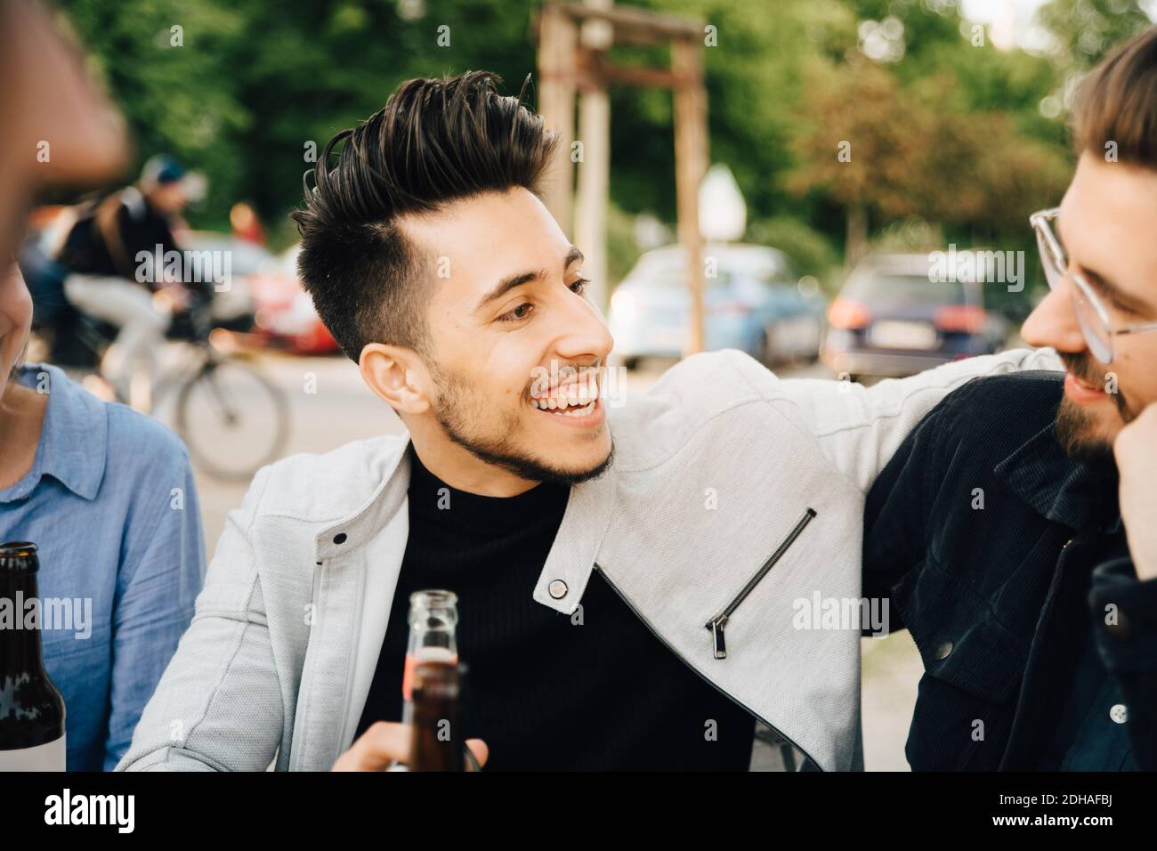 Young man looking at male friend while sitting at garden party Stock Photo