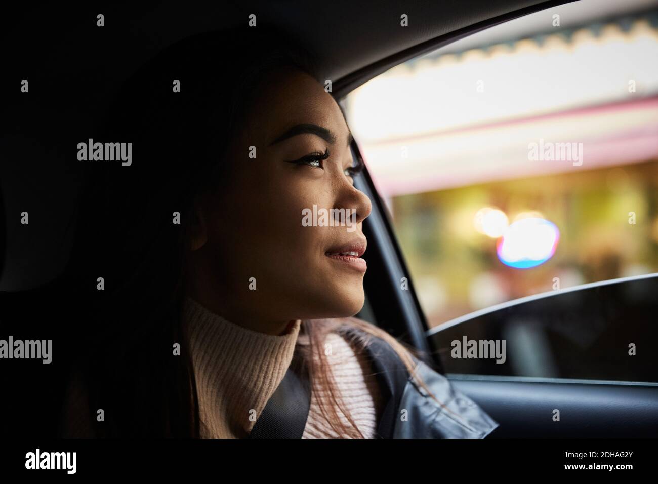 Thoughtful young woman looking through window while sitting in car Stock Photo