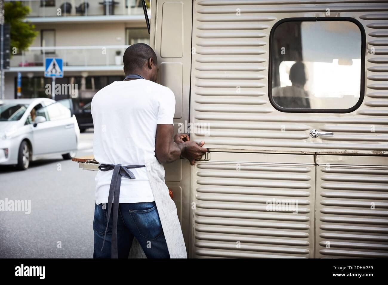 Male owner unlocking door of food truck on city street Stock Photo