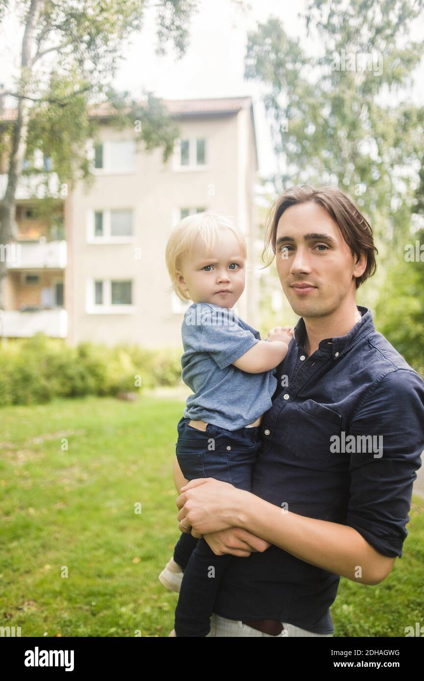 Portrait of man carrying baby boy at park Stock Photo