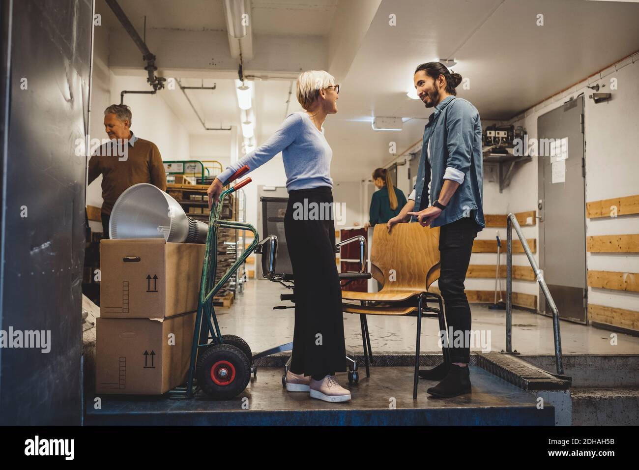 Businessman and businesswoman talking while moving into new office Stock Photo
